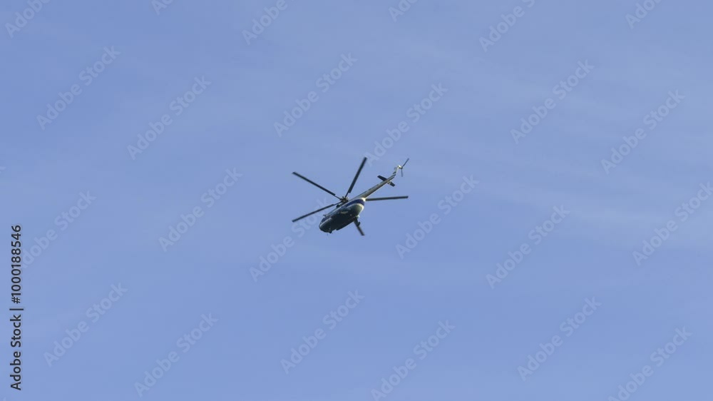A large helicopter captured mid-flight with clear visibility against a bright blue sky. The low-angle shot shows the helicopter's structure in motion, highlighting its propellers and tail in action A large helicopter captured mid-flight with clear visibility against a bright blue sky. The low-angle shot shows the helicopter's structure in motion, highlighting its propellers and tail in action