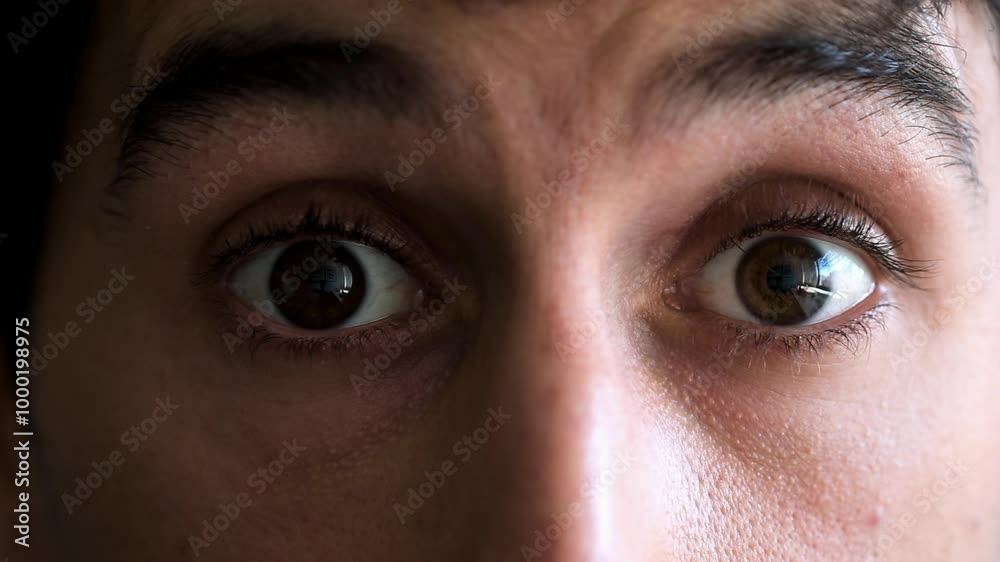 Man's eyes open wide in a close-up, showing a look of surprise or shock. His expression is intense and dramatic, highlighting an unexpected moment of realization or astonishment