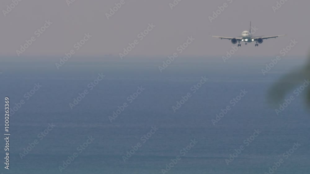 Long shot of commercial airplane landing from sea, front view. Airliner flying over the sea. Airfield on the coast of the island Long shot of commercial airplane landing from sea, front view. Airliner flying over the sea. Airfield on the coast of the island