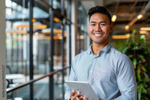Happy young Pacific Islander business man executive holding tablet at the office. , background blur