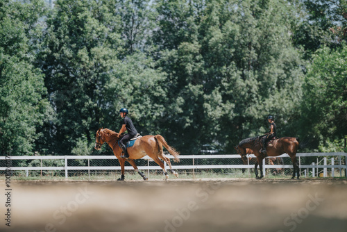 Two equestrians riding horses at an outdoor training facility surrounded by lush green trees, practicing their horseback riding skills.