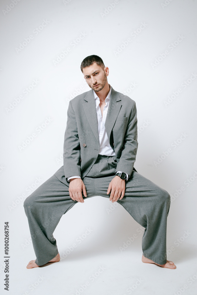 Fashion man model in grey suit, barefoot, shoot in studio Fashion man model in grey suit, barefoot, shoot in studio