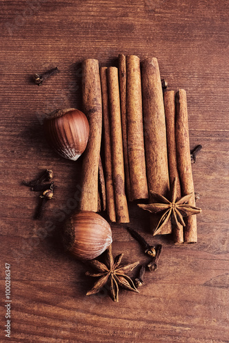 image with fragrant cinnamon sticks, hazelnuts, clove buds and star anise on a wooden background close-up, top view