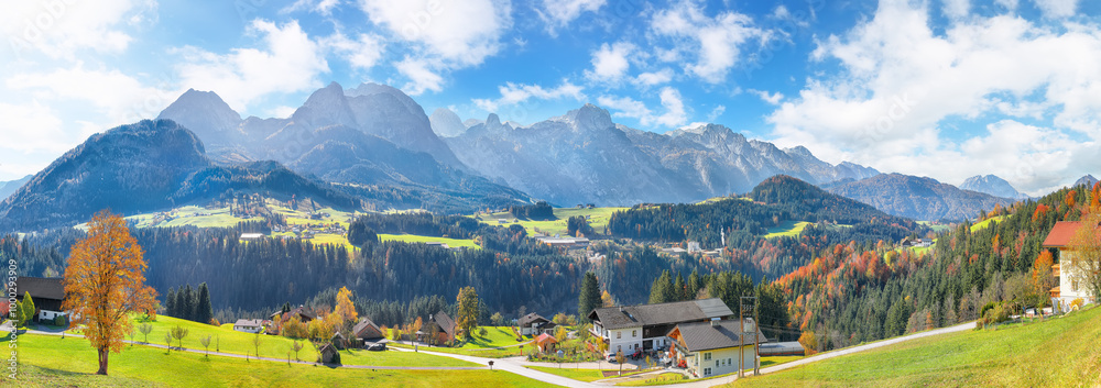 Captivating view of Alpine green fields and traditional wooden houses near Abtenau village at autumn sunny day.