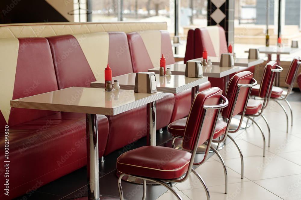 Interior of retro-style American diner with red leather booths and shiny dining tables, ketchup bottles, and classic diner decor creating nostalgic atmosphere Interior of retro-style American diner with red leather booths and shiny dining tables, ketchup bottles, and classic diner decor creating nostalgic atmosphere