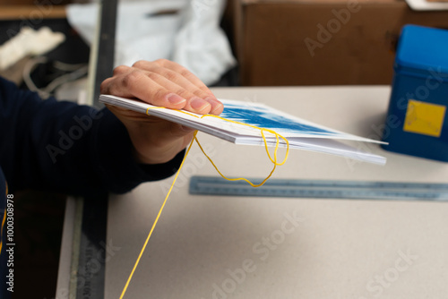 Photography Artisan binding a book using traditional Japanese bookbinding techniques with yellow thread and white paper