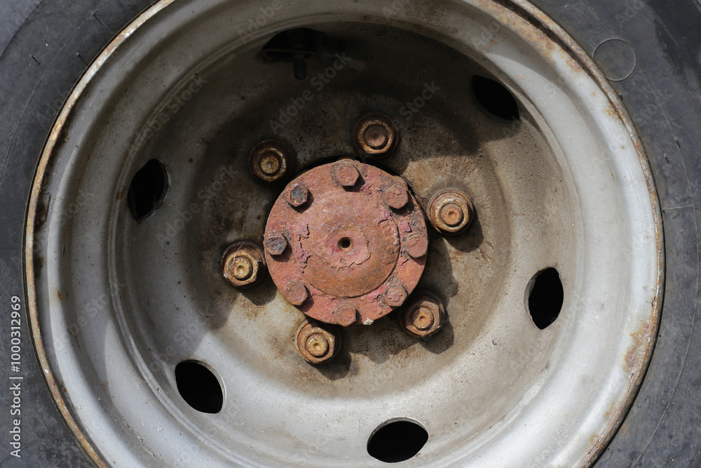 Rusty truck wheel rim and cracked tire. Grunge detail truck tyre. Transportation industry. Weathered and worn vehicle parts. Damaged car wheel. Dangerous to drive. Rusty bolts in a circle shape. Rusty truck wheel rim and cracked tire. Grunge detail truck tyre. Transportation industry. Weathered and worn vehicle parts. Damaged car wheel. Dangerous to drive. Rusty bolts in a circle shape.