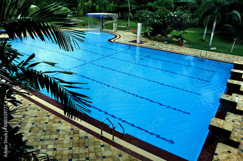 A serene swimming pool atmosphere, perfect for family vacations, featuring crystal-clear water, adorned with plants and a pavilion for relaxing and enjoying a sunny day