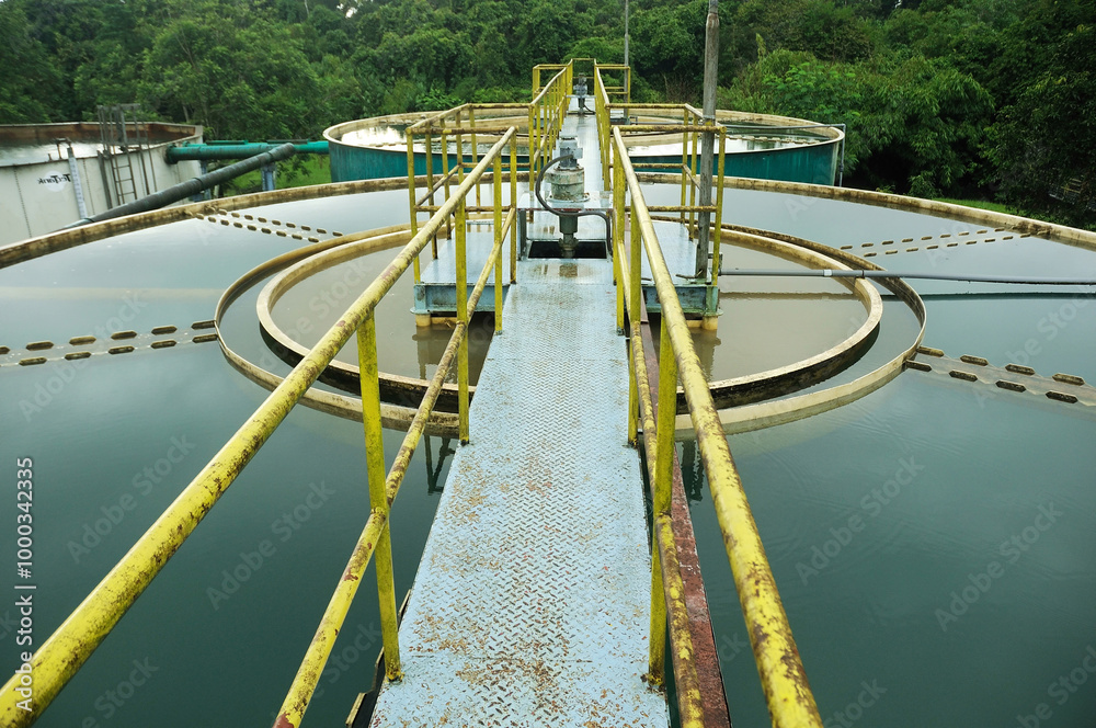 Naklejka premium a water treatment facility featuring several large storage tanks filled with water. Surrounding the tanks are large green pipes, likely used to transfer water between the tanks