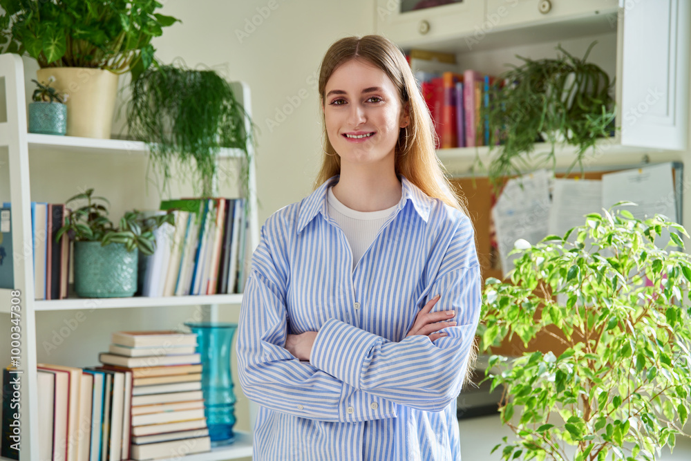 Portrait of smiling female teenager looking at camera with crossed arms in home Portrait of smiling female teenager looking at camera with crossed arms in home