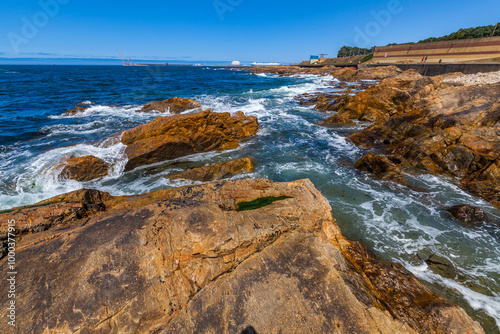 Waves crash against rocky outcrops in the blue ocean