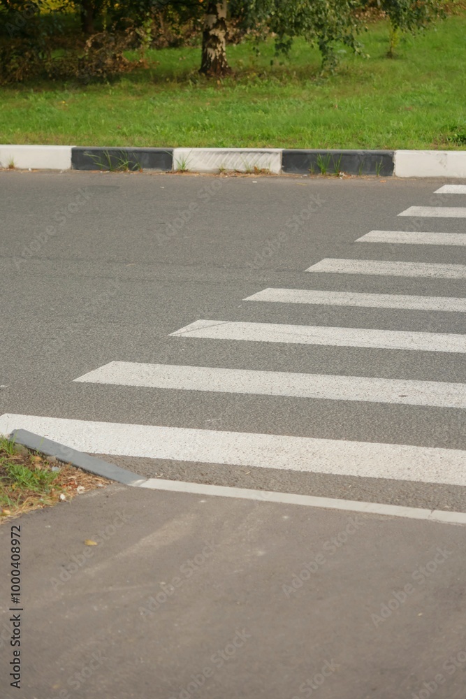 Obraz premium pedestrian crosswalk with white marking lines on asphalt dark road. road markings, zebra crossing, place to cross the road, traffic rules. safety of pedestrians and motorists.