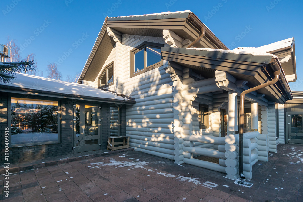 A delightful house made of painted white logs in the rays of the sun on a clear winter .day. A delightful house made of painted white logs in the rays of the sun on a clear winter .day.