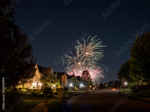 Evening fireworks over an American neighborhood with warm lights. photo
