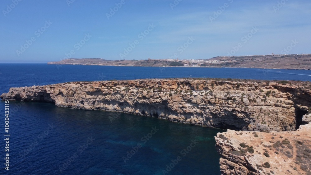 Aerial view of the sea caves of Cominotto uninhabited island near Comino, Maltese islands. Seagull flying in the frame. High quality photo