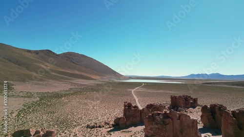 Aerial view of the dirt road between the Laguna Vinto high alitude lake and the Italia Perdida volcanic rock formation in Bolivia, on the Andean plateau