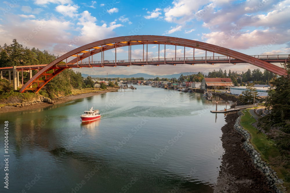 Naklejka premium Historic Rainbow Bridge in the tourist town of La Conner, Washington with a boat passing underneath. The bridge connects the town to the island that is part of the Swinomish Indian Reservation.