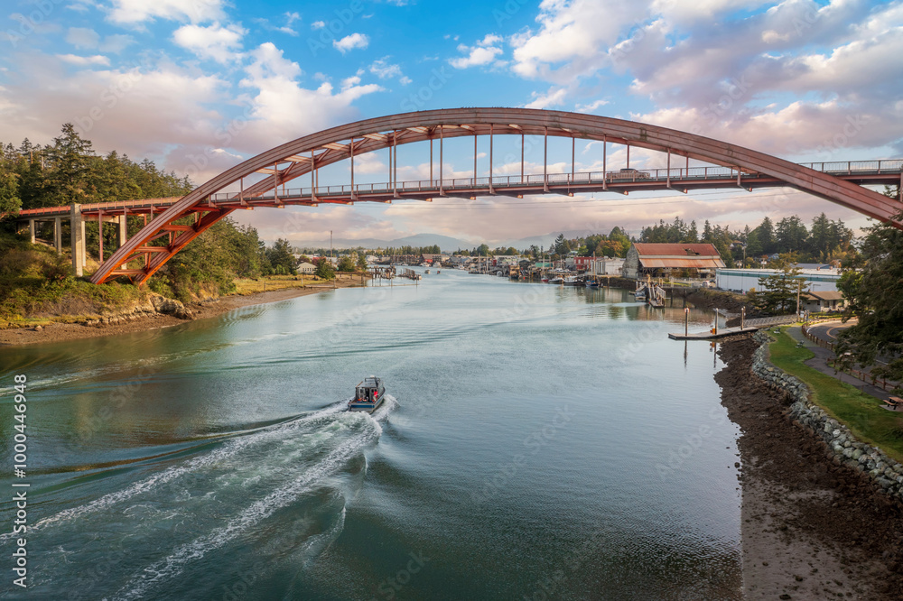 Obraz premium Historic Rainbow Bridge in the tourist town of La Conner, Washington with a boat passing underneath. The bridge connects the town to the island that is part of the Swinomish Indian Reservation. 