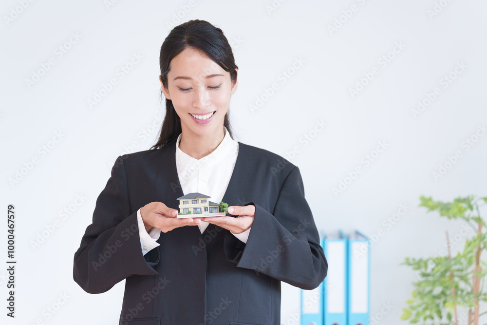 家の模型を持つ不動産営業マン女性 家の模型を持つ不動産営業マン女性