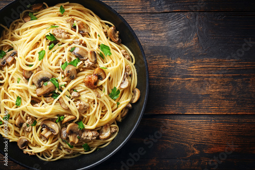 Piatto scuro di spaghetti con sugo di carne, funghi e prezzemolo, su un tavolo di legno scuro. Vista ravvicinata dall'alto.