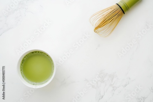 Matcha tea cup and a bamboo whisk on a white marble background, top view