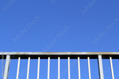 Metal fence against a clear blue sky textured abstract background