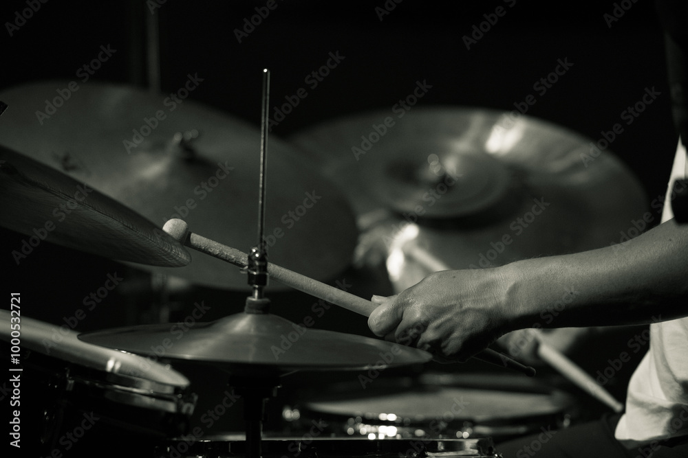 Obraz premium Black and white close-up of a drummer's hands playing cymbals during a live performance, focusing on the motion and rhythm.