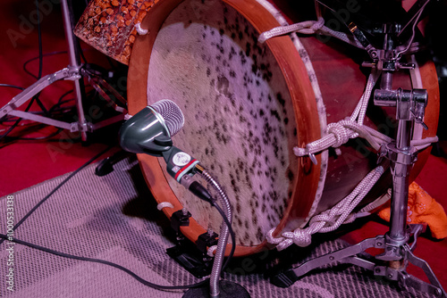 Close-up of a traditional drum and microphone setup on stage, focusing on the detailed texture of the drum skin and ropes. photo