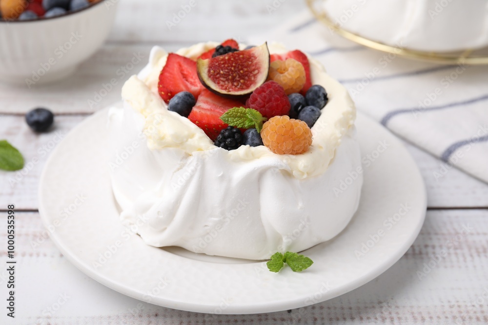 Pavlova cake (meringue dessert) with whipped cream, fresh berries, fig and mint on white wooden table, closeup Pavlova cake (meringue dessert) with whipped cream, fresh berries, fig and mint on white wooden table, closeup