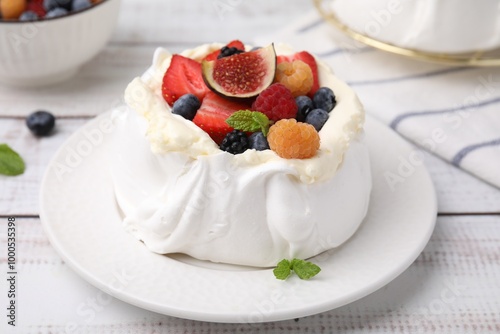 Pavlova cake (meringue dessert) with whipped cream, fresh berries, fig and mint on white wooden table, closeup