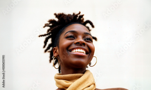 Young woman with dark skin and curly hair wearing a tan scarf and gold hoop earrings, smiling warmly.