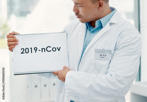 Man, doctor and hands with sign for covid, pandemic or start of year or virus at hospital. Closeup, medical professional or healthcare employee with poster, page or paper for post or pre coronavirus photo