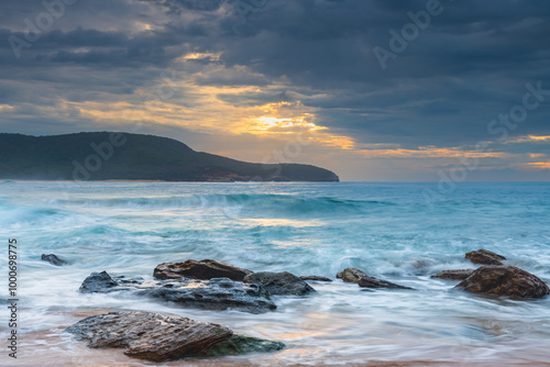 Sunrise at the seaside with rocks and beautiful diffused light by the rain clouds