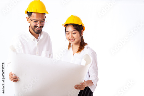 Young engineer and architect holding and working together on building site blueprint at construction site or factory.	