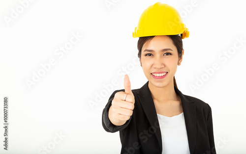 Portrait Pretty Asian Architect Woman with black suit and yellow safety helmet show her thumbs up in approval, give permission, recommend construction company,  isolated over white background