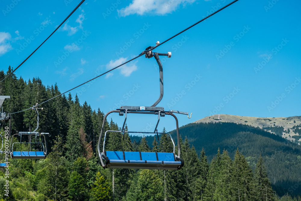 A sunny day in the mountains with a scenic ski lift overlooking lush greenery and distant peaks