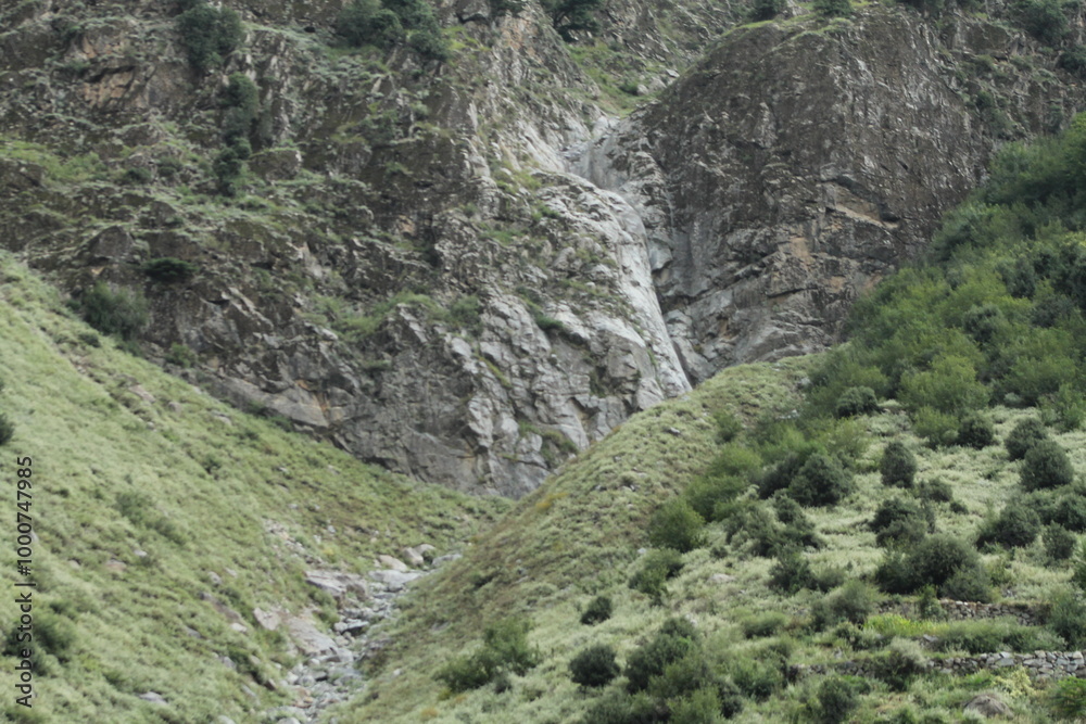 A rugged black stone formation on a barren mountainside, devoid of trees or vegetation. A rugged black stone formation on a barren mountainside, devoid of trees or vegetation.