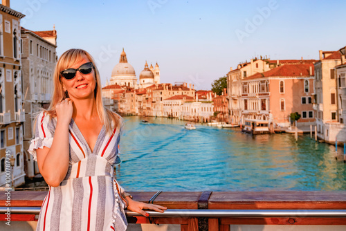 A stunningly beautiful woman poses gracefully beside the iconic Grand canal of Venice, capturing a perfect summer evening
