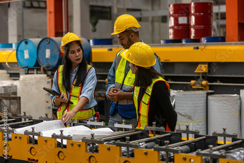 Three mechanical engineers from different ethnicities having conversation over the master plan using technology to manage a machinery system. Collaboration among 3 technicians over a metal factory