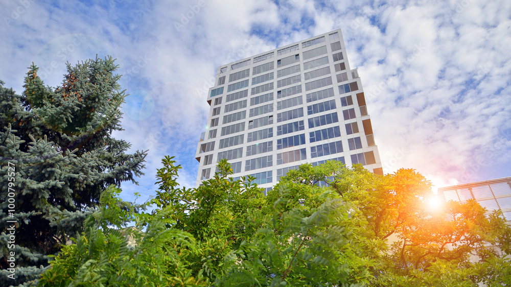 Exterior of a high modern multi-story apartment building - facade, windows and balconies. Eco-friendly living in city with greens. Exterior of a high modern multi-story apartment building - facade, windows and balconies. Eco-friendly living in city with greens.