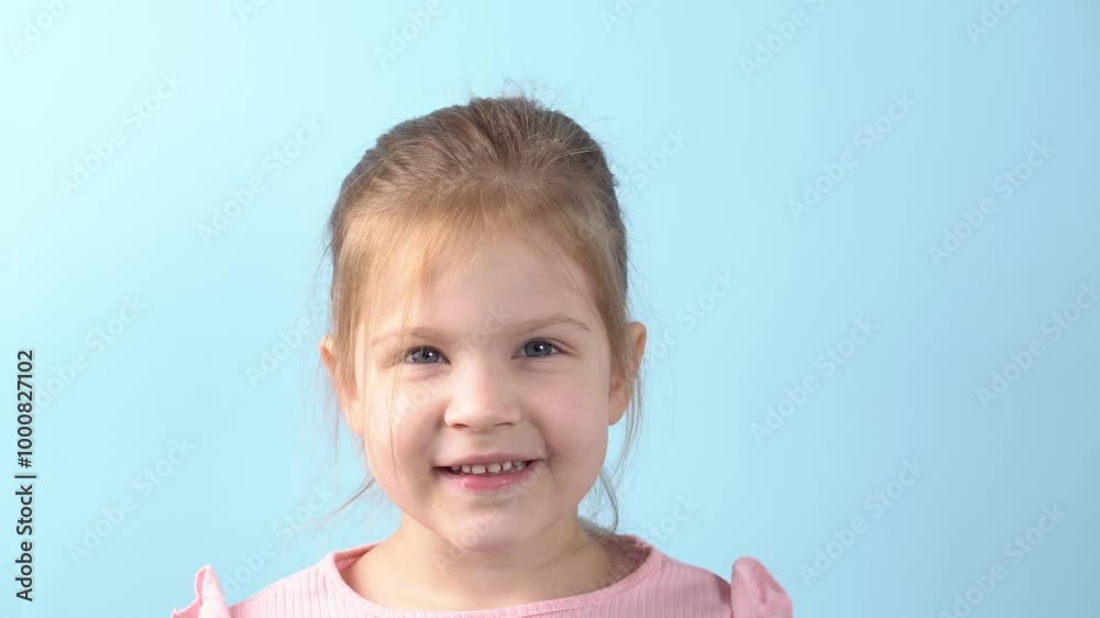 Portrait of little girl child waving hand gesturing hello smiling to camera on blue background. Toddler girl smiling and waving hand looking at camera Portrait of little girl child waving hand gesturing hello smiling to camera on blue background. Toddler girl smiling and waving hand looking at camera