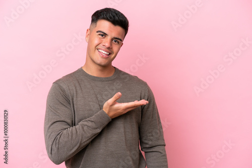 Young caucasian handsome man isolated on pink background presenting an idea while looking smiling towards