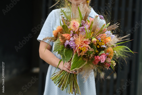 A large bouquet of mixed flowers in the hands of a woman. The work of a florist in a flower shop