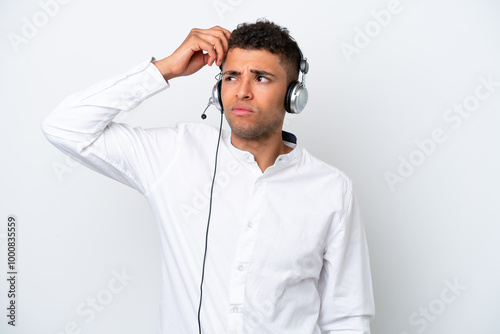 Telemarketer Brazilian man working with a headset isolated on white background having doubts and with confuse face expression