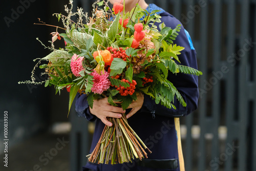 A large bouquet of mixed flowers in the hands of a woman. The work of a florist in a flower shop