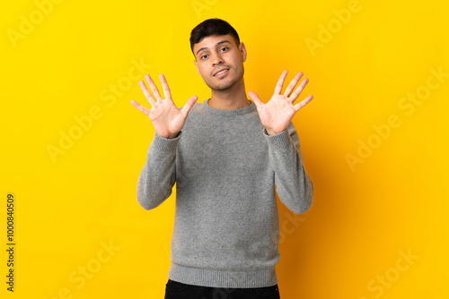 Young Colombian man isolated on yellow background counting ten with fingers photo