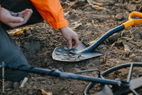 A man puts coins found with a metal detector on a shovel.