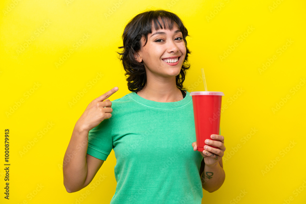 Young Argentinian woman holding a soda isolated on yellow background giving a thumbs up gesture Young Argentinian woman holding a soda isolated on yellow background giving a thumbs up gesture