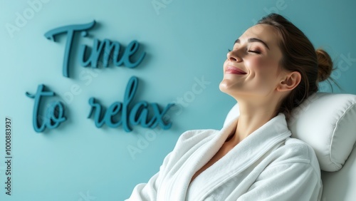 A woman dressed in a white robe relaxes in a spa setting with a 'Time to relax' sign on the wall behind her in a serene environment designed for rejuvenation and peace. photo