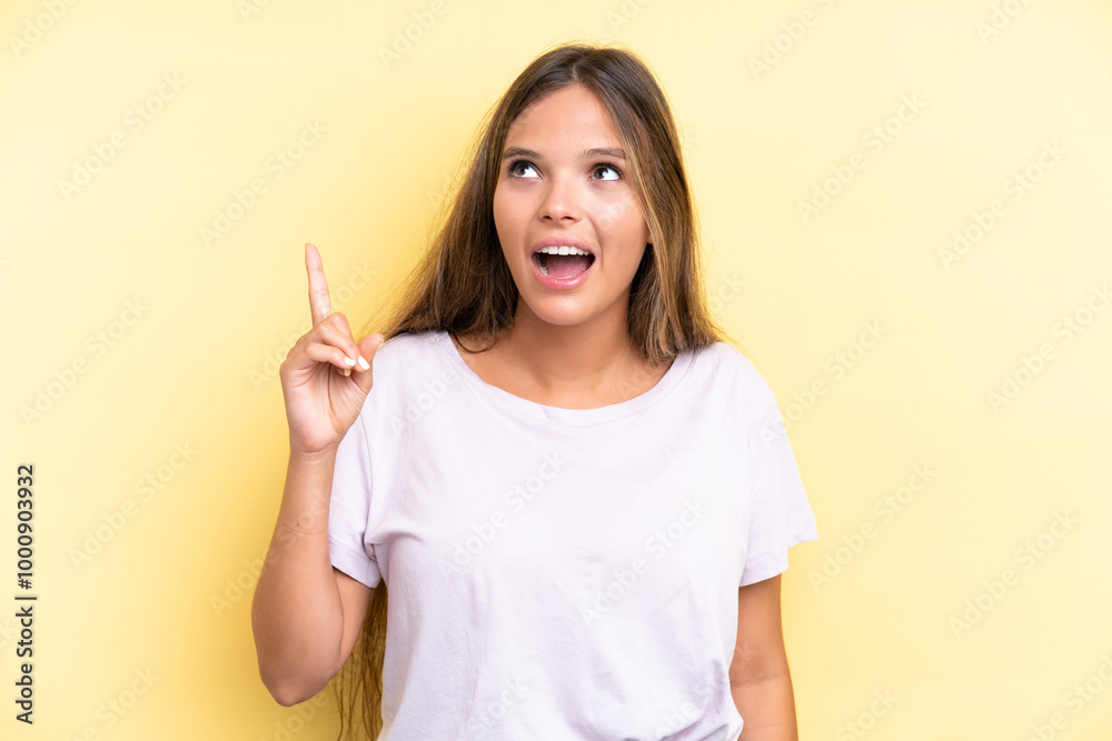Young caucasian woman isolated on yellow background pointing up and surprised Young caucasian woman isolated on yellow background pointing up and surprised